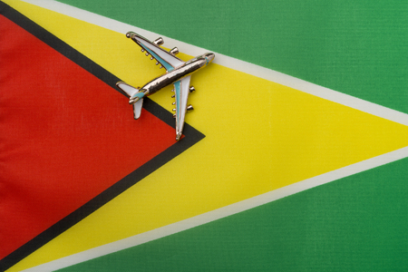 Plane over the flag of Guyana, the concept of travel and tourism. Toy plane on the flag in the background.の写真素材