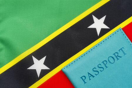 A passport stands against the flag of Saint Kitts and Nevis. The concept of travel and tourism.の写真素材