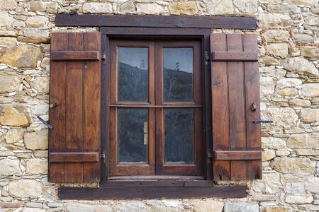 An old window with wooden shutters in a stone house. Stone building and old wooden window.の写真素材