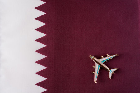 Plane over the flag of Qatar travel concept. Toy plane on a flag in the background.