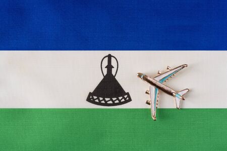 Plane over flag of Lesotho travel concept. Toy plane on a flag in the background.の写真素材