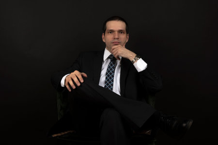 A man in a black suit on a black background. A handsome male businessman in an elegant black suit.