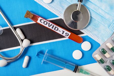 Coronavirus, the concept COVid-19. A protective breathing mask, stethoscope, syringe, and tablets on the flag of Botswana are visible from above .の写真素材