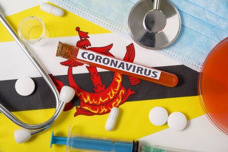 Coronavirus, nCoV concept. Top view protective breathing mask, stethoscope, syringe, tablets on the flag of Brunei Darussalam.の写真素材