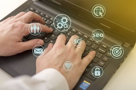 Social media and Marketing virtual icons screen concept. Close up of businessman typing keyboard with laptop computer on wooden desk in modern officeの写真素材