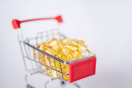 Cod liver oil omega 3 gel capsules in a shopping cart on white background. The concept of health and happiness.の写真素材