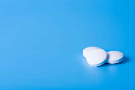 three anti-inflammatory pills on blue background. The concept of health and happiness.の写真素材