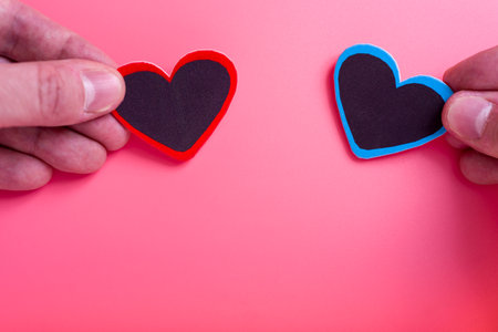 A man's hand holds a heart on an isolated pink background. Concept of Valentine's day and mother's day. The concept of love and loyalty.の写真素材