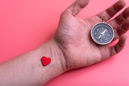 The compass on the palm of your hand on pink background. The concept of direction in love.の写真素材