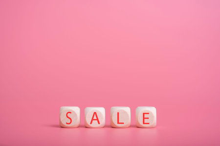 Wooden cubes on a pink background, on them the word SALE is written. The concept of sales, service...