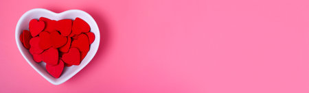 hearts in a saucer in the shape of a heart on a pink background. Concepts of love and happiness on...