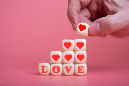 love valentine's day conceptman hand holding the heart to put on the cube wooden to mean the love on...