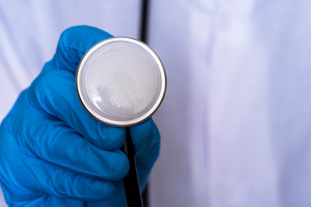 A hand in a medical glove pulls a medical mask from under a stethoscope, the concept of having to wear a medical mask.の写真素材