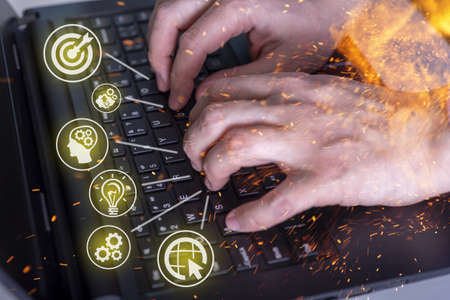 Hands on a laptop and an idea. Hands close-up and fire, work at home, burnout. The concept of working from home.の写真素材