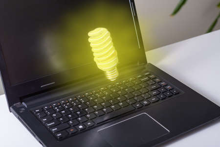 Computer on desktop in office with bulb icon hologram. Multi exposure. Concept of idea. The concept of the idea.の写真素材