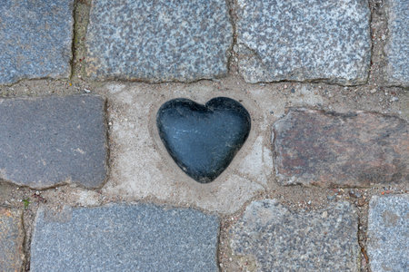 Black zen heart shaped rock on a tile background. The concept of love and happiness.の写真素材