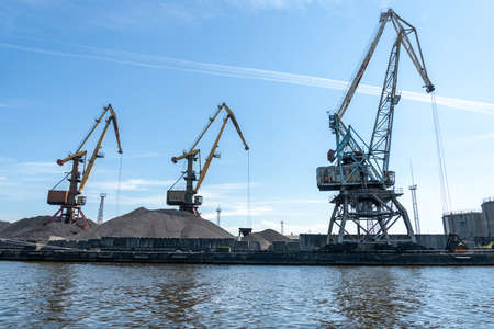 Many tall cargo cranes stand on the banks of the Venta River. Ventspils, Latvia, Baltic Sea. Copy spaceの写真素材