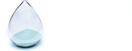 Hourglass on white background. Sand falls inside an azure-colored flask. The place under the...