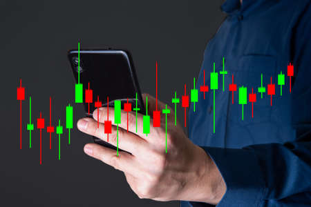 The hand of a businessman or trader shows a growing virtual hologram of stocks on a smartphone, planning and strategy, stock market. Business growth, the concept of progress or success. invest in trading.の写真素材
