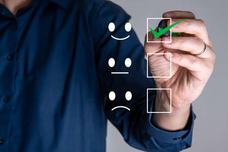 The businessman draws a tick on the icon with a cheerful smile. The concept of a good choice.の写真素材