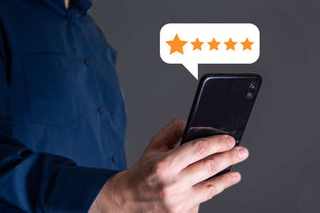 close up Man hand using smartphone with popup five star icon for feedback review satisfaction service, Customer service experience and business satisfaction survey.の写真素材