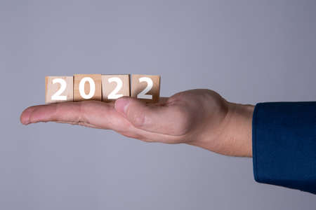Happy New Year 2022 theme men's hands holding wooden cubes with the number 2022 on the palm. The concept of the new 2022.の写真素材