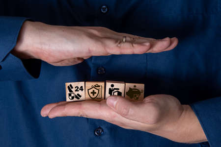 The hand holds wooden cubes with insurance icons. The concept of life insurance and medicine.の写真素材