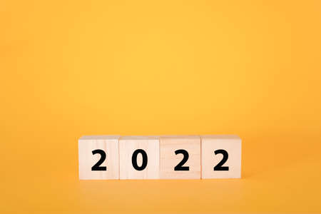Wooden cubes on a yellow background and 2022. The concept of the New Year and holiday.の写真素材