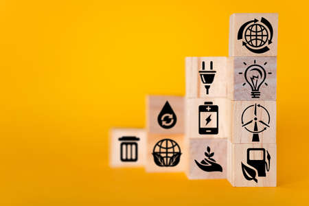 Ecology concept with icons on wooden cubes, yellow background. The concept of clean energy for the whole world.の写真素材