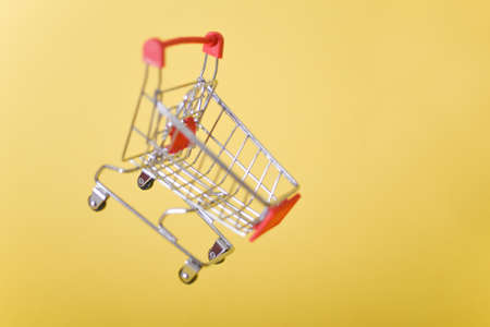 cart, hand-cart, shopping cart, trolley on a yellow background. concept buyer, Shopper. purchasing power, demand, shopping concept. Copy spaceの写真素材