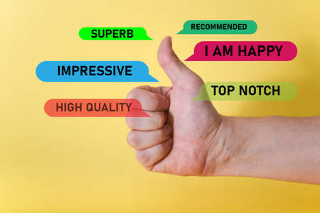 A hand showing a thumbs-up sign on a yellow background. Well done, a good concept of work.の写真素材