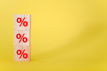 Percent sign on wooden cubes against yellow background. Business and finance discount or interest rate concept.の写真素材
