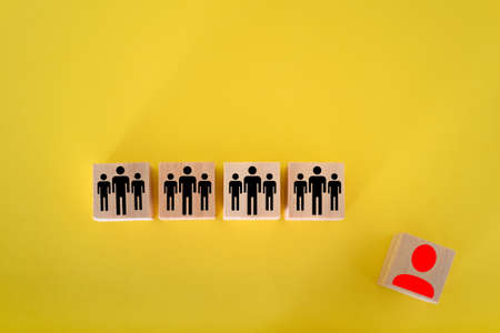 Head hunting and leadership concept. Wooden cube block with human icon symbol on a yellow background.の写真素材