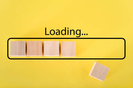 Loading the progress bar with wooden cubes. Download progress. Loading status on a yellow background.の写真素材
