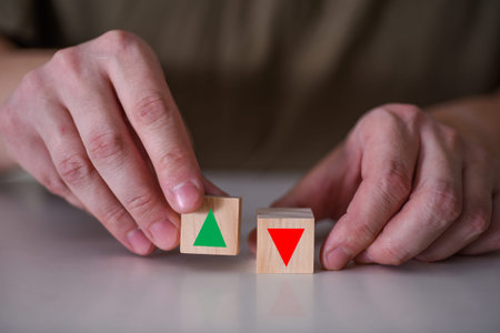 A businessman holds a red and green arrow symbol on a wooden cube. The concept of trading in the...