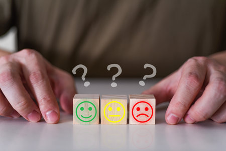 Smiling, indifferent and sad emoticons on wooden cubes under a question mark. The concept of satisfactionの写真素材