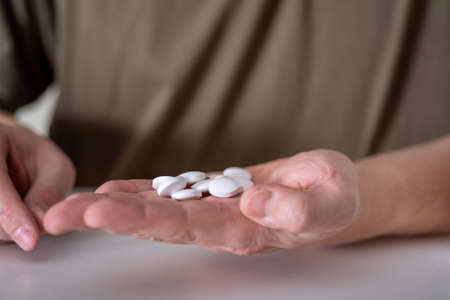 A handful of pills in the hands of the person sitting opposite. The concept of taking medications.の写真素材