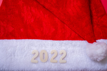 Santa's hat and the numbers of 2022 on a red background. The concept of the new year.