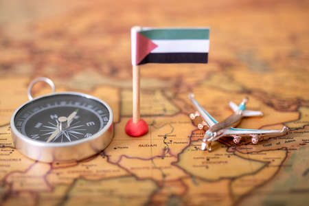 Flag of Sudan, plane and compass on the world map. The concept of travel and tourism.の写真素材