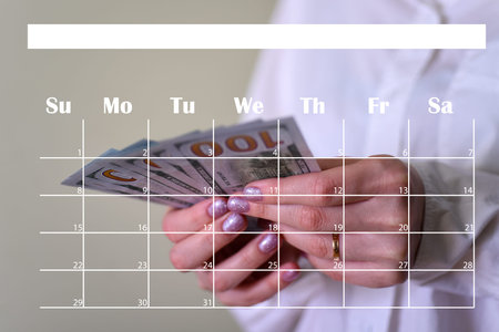 Money in the hands of a woman and a calendar. The concept of paying a loan or receiving a salary.