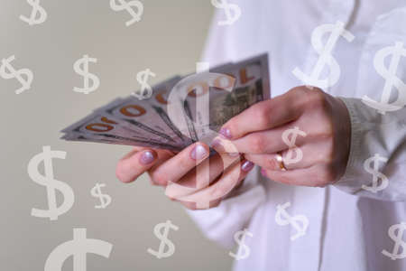 Paper money dollars in a woman's hand close up, calculating finance. The concept of keeping records of money in women's hands.の写真素材