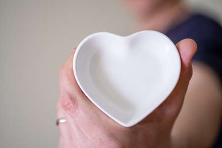 Close-up of a man holding a heart-shaped saucer. The concept of love and fidelity.の写真素材