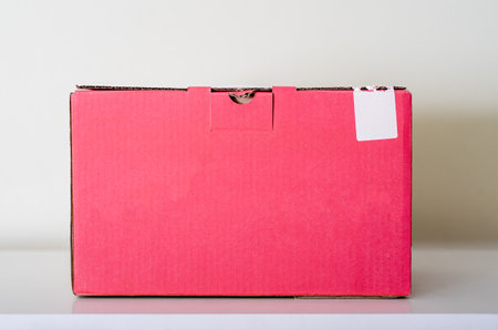 Pink cardboard box on a white table and a light background. The concept of delivering goods to any place.の写真素材