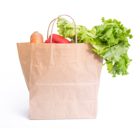 Fresh vegetables in paper shopping bag on white background. The concept of healthy food.の写真素材