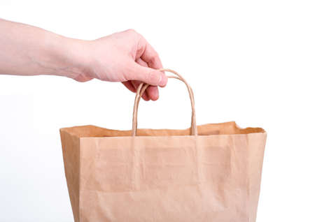 Hand hold brown kraft paper bag on white wall background.の写真素材