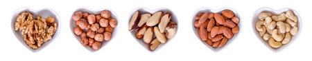 A collection of nuts in cups in the shape of a heart on a white background. The concept of healthy food.の写真素材