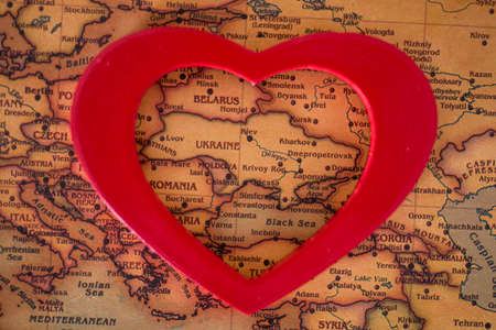 heart with national flag of ukraine on a vintage world map crack paper background. The concept of love for Ukraine.の写真素材