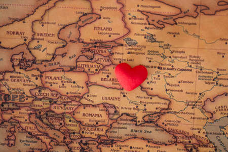 heart with national flag of ukraine on a vintage world map crack paper background. The concept of love for Ukraine.の写真素材