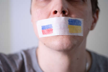 Scotch-taped mouth with the flag of Russia and Ukraine, trying to say. The concept of freedom of the press in Russia.の写真素材