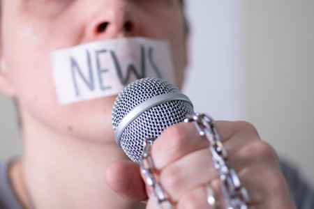 A man gags his mouth with duct tape saying news trying to speak into a microphone. The concept of World Press Freedom Day.の写真素材